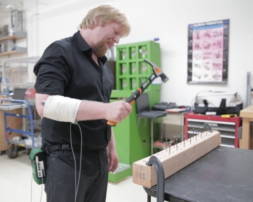 Man holding Fiskars hammer hitting nails in a lab setting