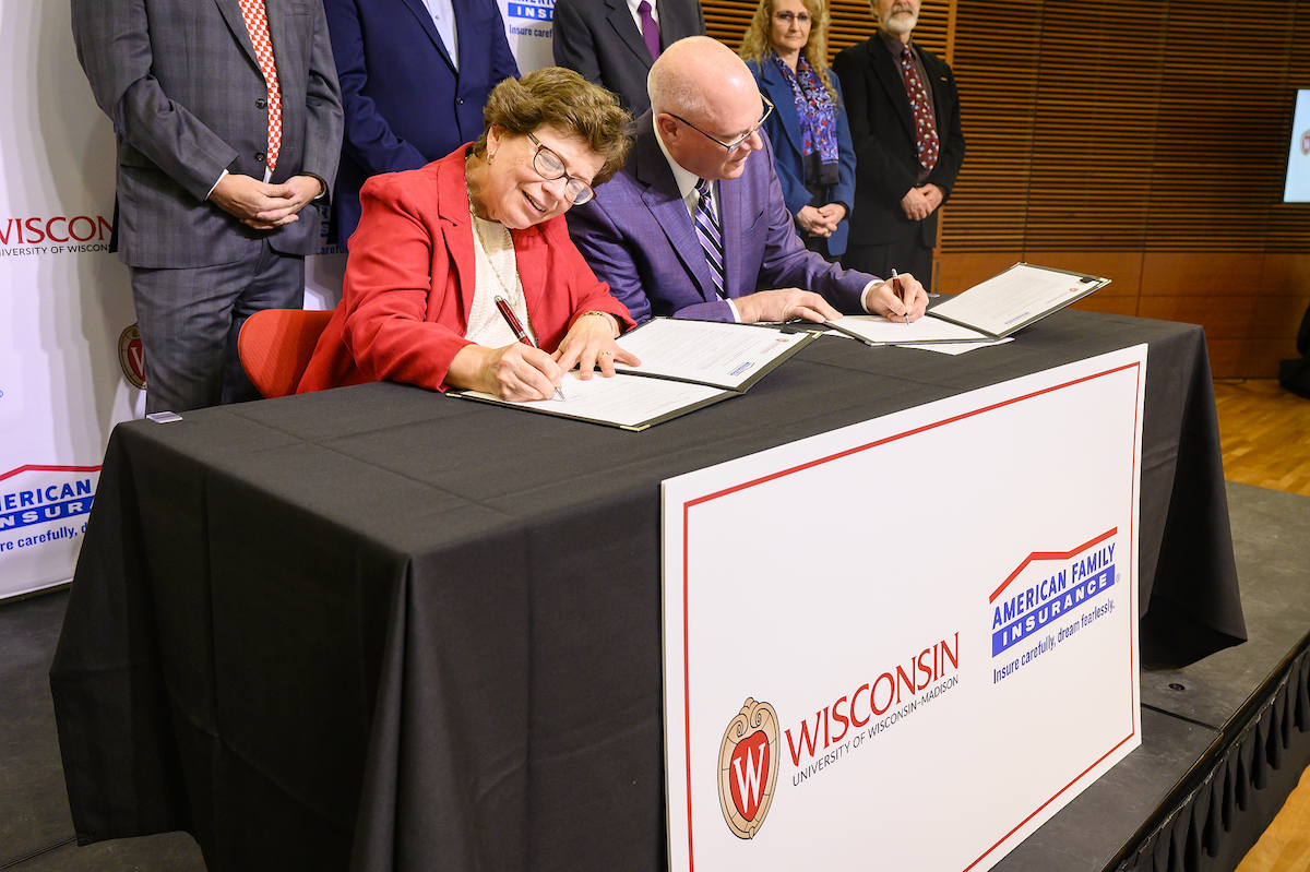 UW–Madison Chancellor Rebecca Blank and Jack Salzwedel, chairman and CEO of American Family Insurance, signing forms on stage