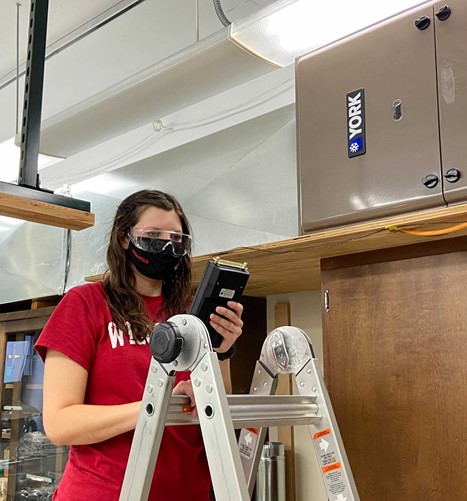 Masters student Stephanie Richards measures air quality near a test furnace