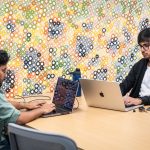 Graduate students work on laptops at CDIS building