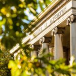 Golden-hued tree foliage frames a view of the front of Agricultural Hall at the University of Wisconsin-Madison