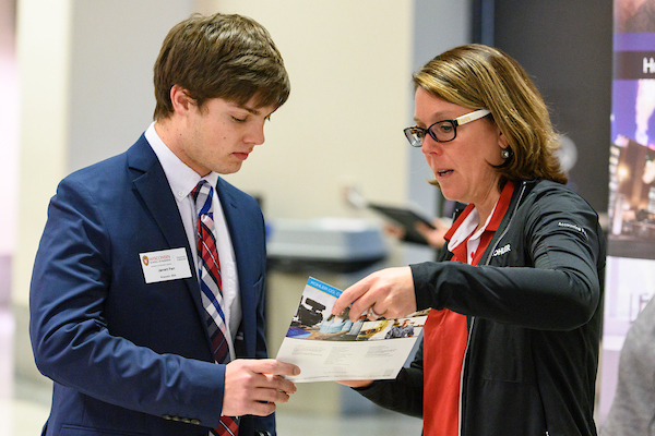 young man listens as woman talks and shows him materials