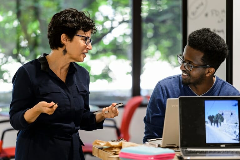 Woman' speaks to man while standing over table of equiptment