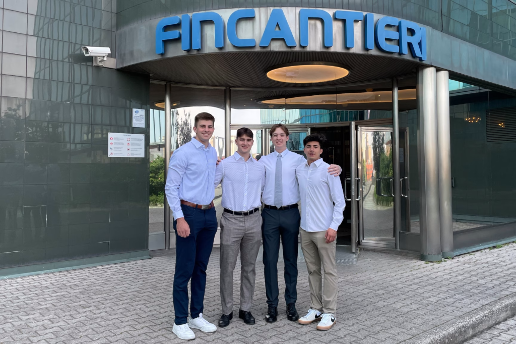 Four people standing in front of the Fincantieri office building entrance.