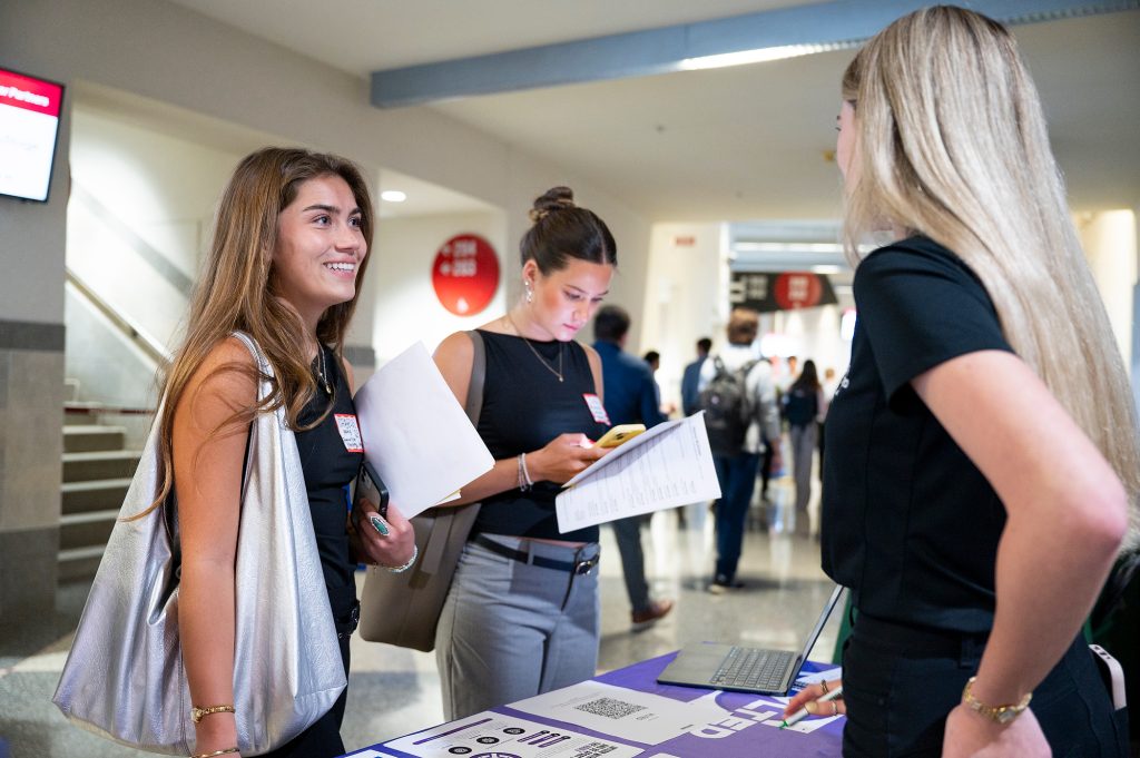 Two students speak to a recruiter at a career fair.