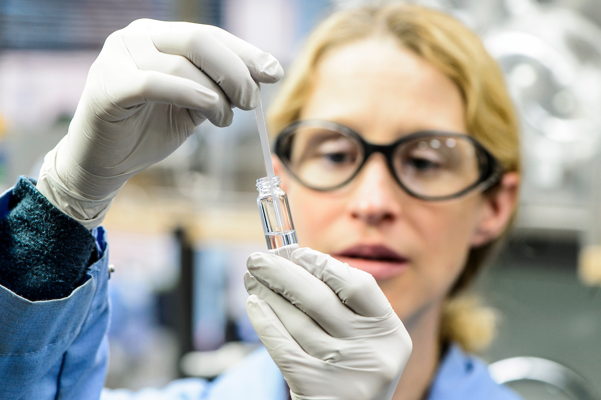 A postdoctoral researcher is pictured with a prototype testing strip