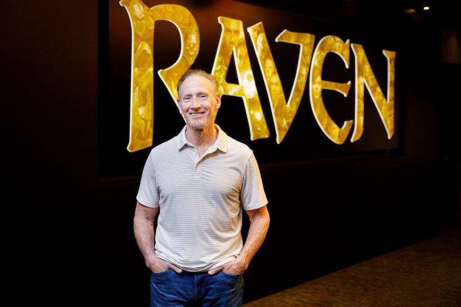 Raven CEO stands in front of a yellow sign that reads "Raven."