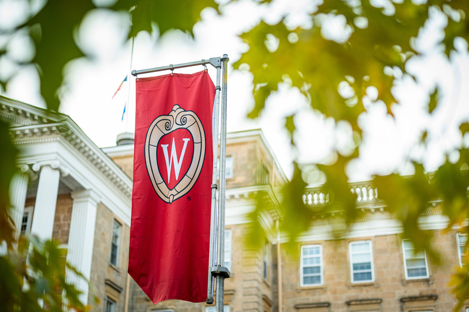 UW crest banner hangs outside of Bascom Hall amid autumn leaves