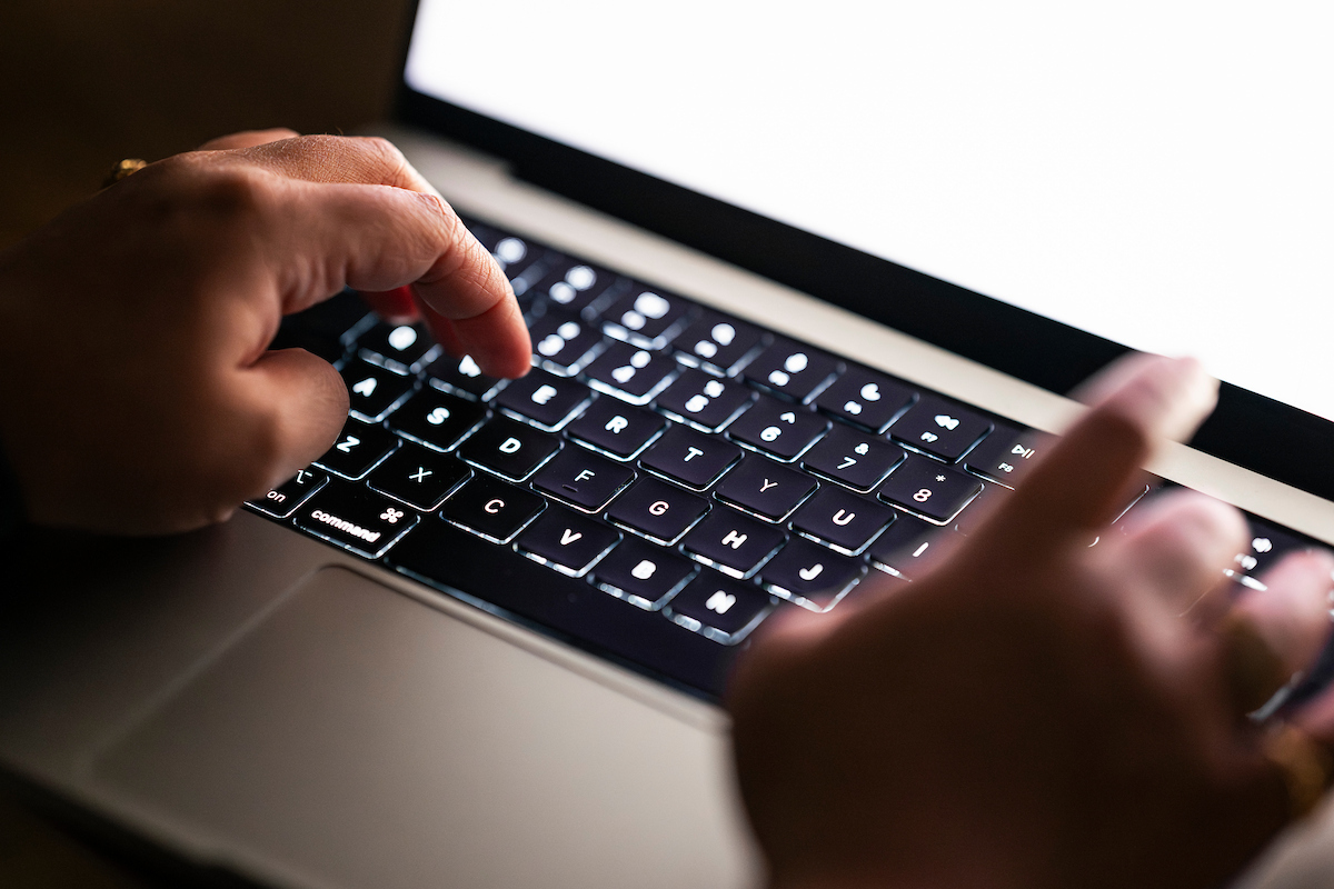 Two hands type on a back keyboard.