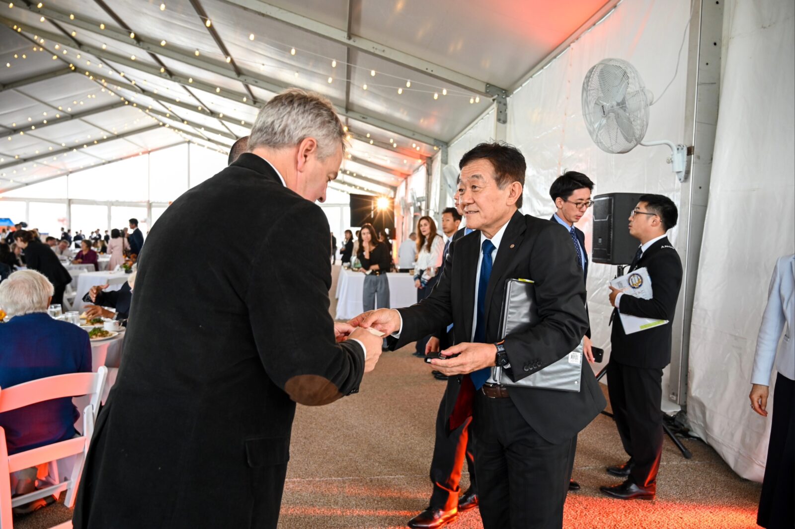 Troy Runge exchanges business cards with Ryohei Tsuji, President & COO of Kikkoman Foods, Inc., inside the event tent.